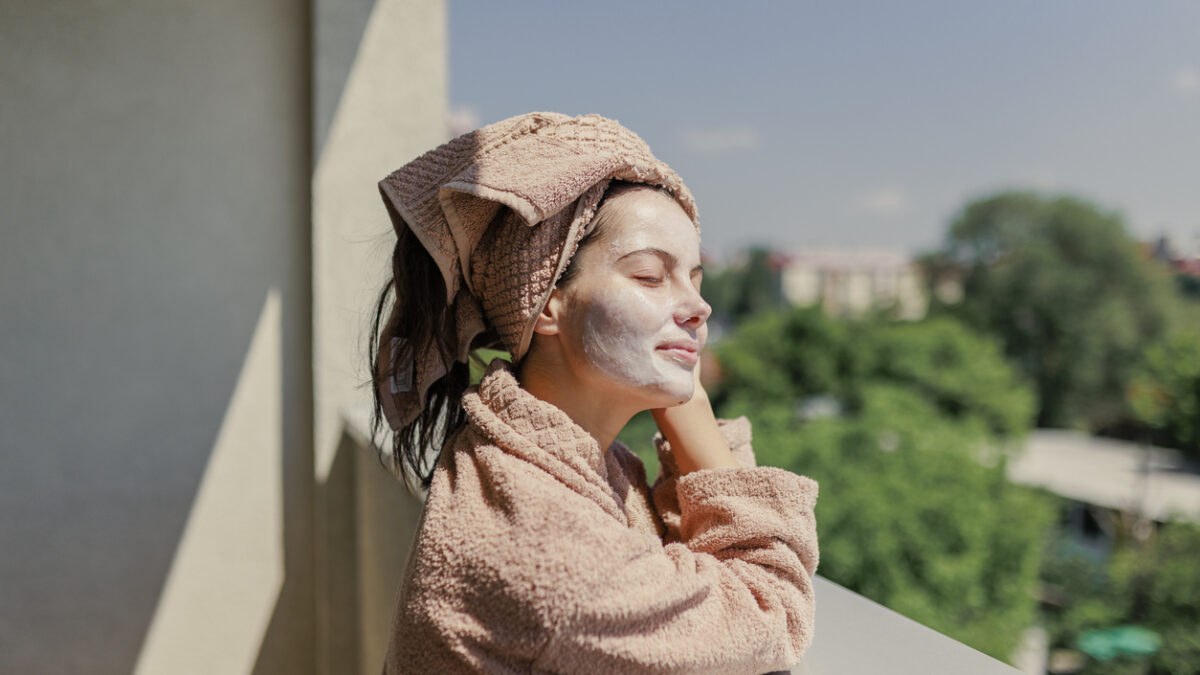 Young woman with face beauty mask taking fresh air on terrace