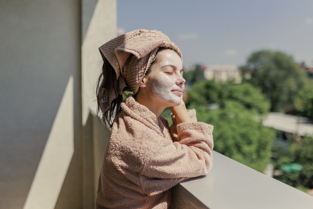 Young woman with face beauty mask taking fresh air on terrace