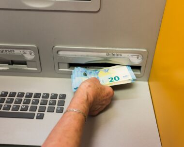 Detail of an elderly woman's hand withdrawing cash from an ATM. Some elderly people have difficulty using ATMs.