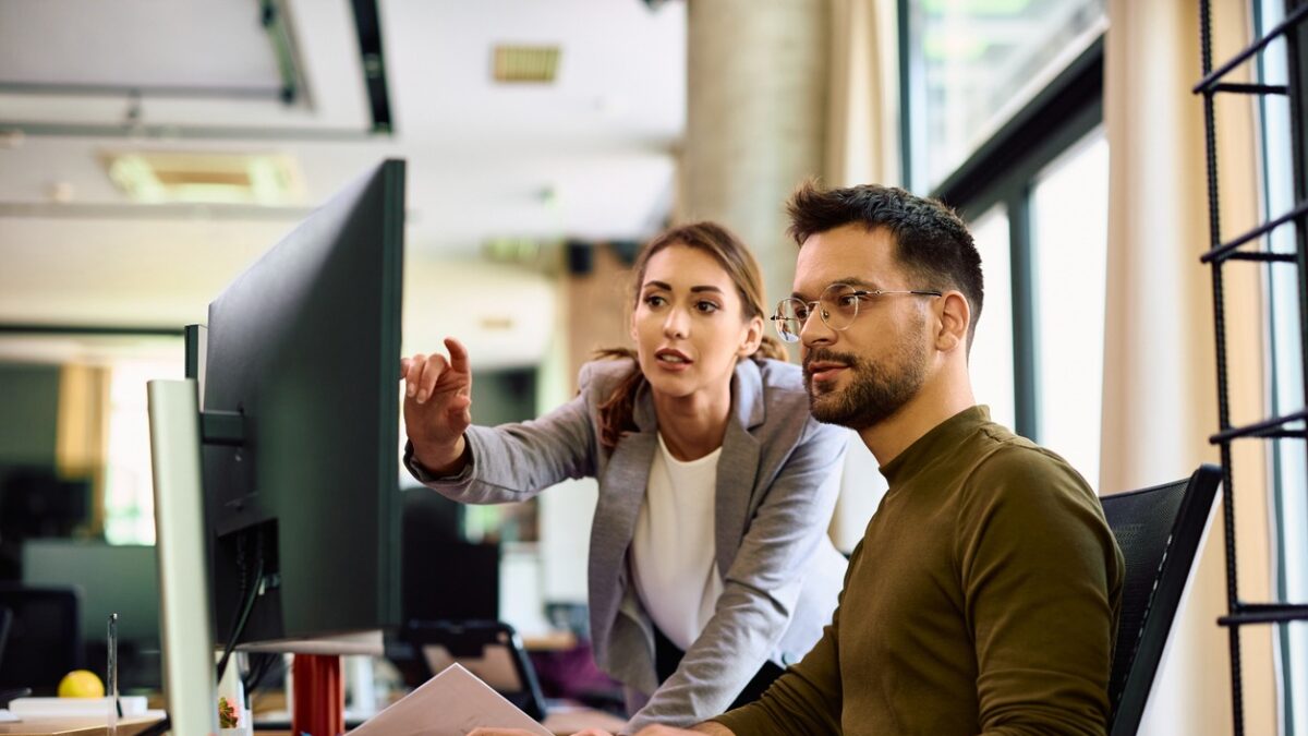Young entrepreneur and his female coworker using desktop PC while working in the office.
