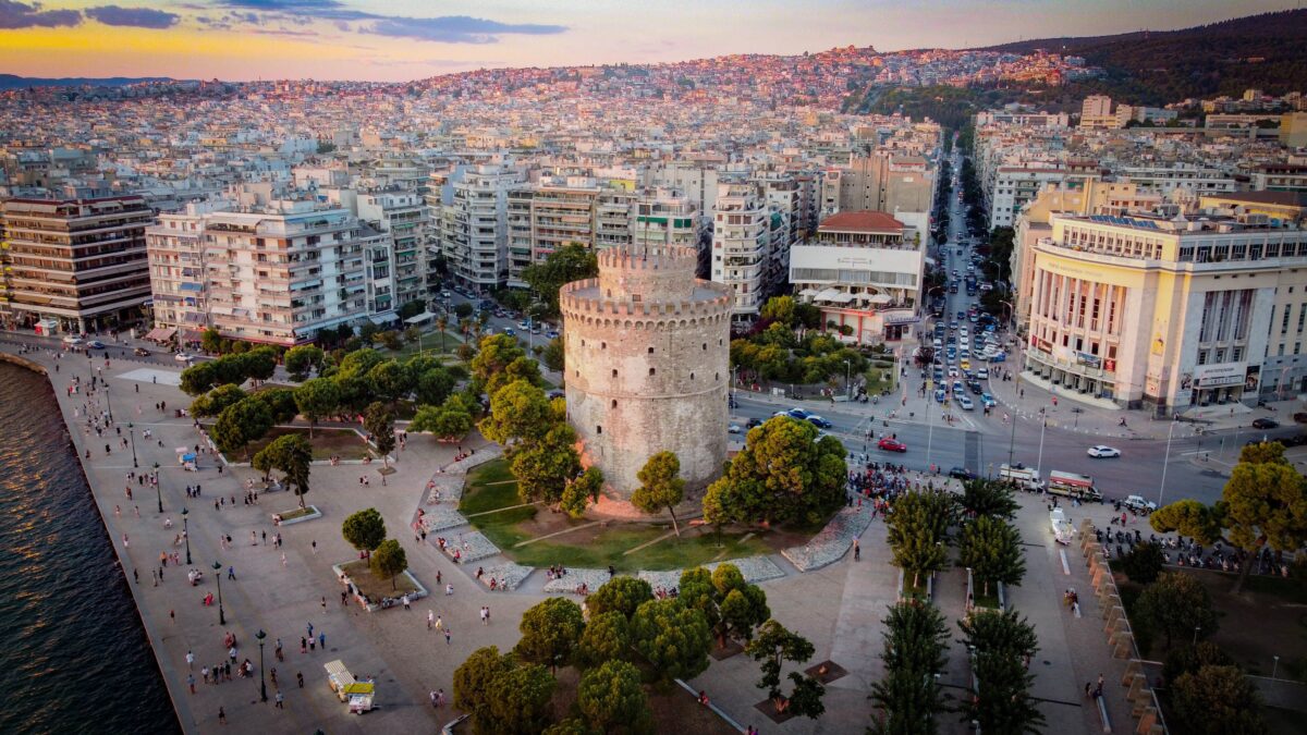 Thessaloniki, Greece – February 10, 2023: An aerial view of the White Tower Of Thessaloniki in Greece, featuring lush green trees and bustling urban cityscape