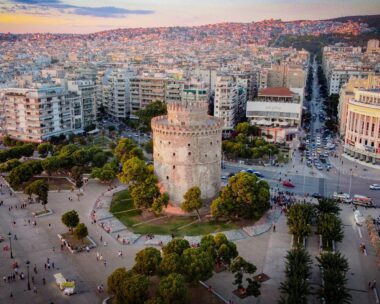 Thessaloniki, Greece – February 10, 2023: An aerial view of the White Tower Of Thessaloniki in Greece, featuring lush green trees and bustling urban cityscape