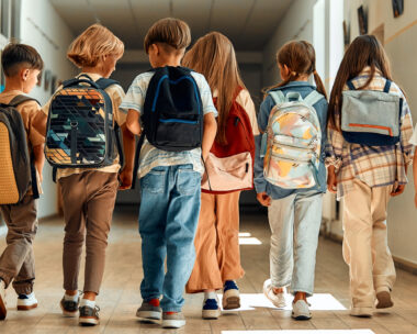 Back to school. A group of schoolchildren with backpacks walk along the school corridor during recess. Education and science concept.