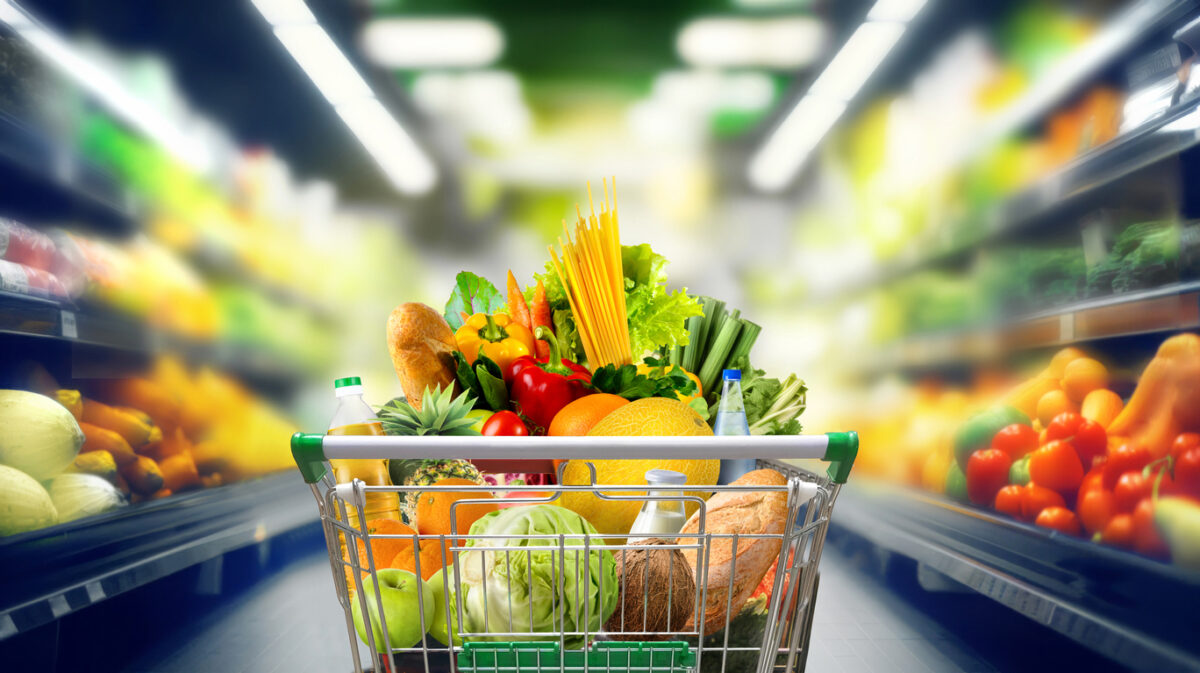 Shopping cart full of groceries at the supermarket aisle.