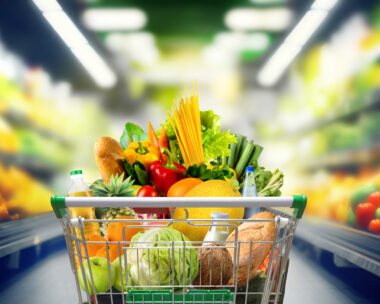 Shopping cart full of groceries at the supermarket aisle.
