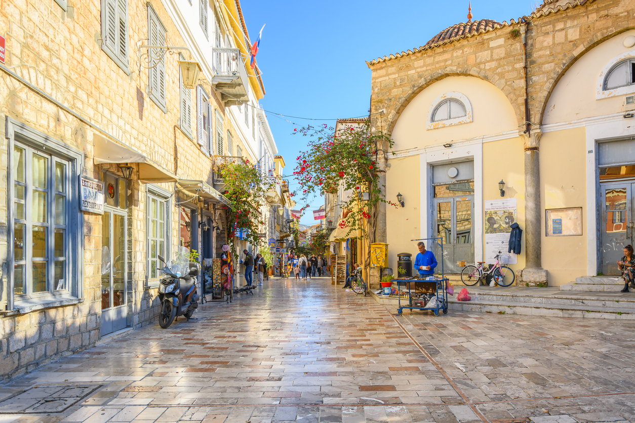 Shoppers on a picturesque street of shops, cafes and businesses in the Old Town village center of the idyllic Greek city of Nafplio, or Nafplion, Greece.