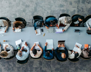 Top view of diverse business group in office meeting, collaborating and discussing around a large table.