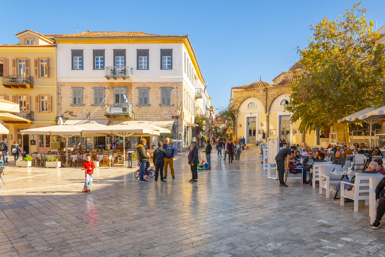 Greeks and tourists enjoy a sunny autumn day at Syntagma Square in the historic old town of Nafplion, Greece in the Peloponnese region.