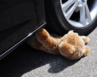 Teddy under car tires, symbolic car accident with playing children