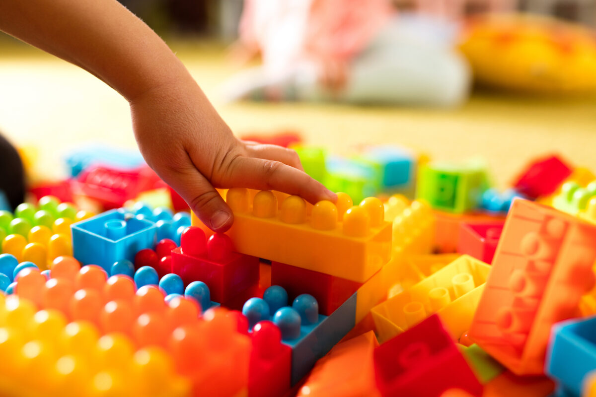 Close-up of unrecognizable child playing with plastic blocks.