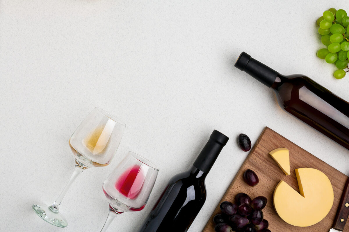 Two wine glasses with red and white wine,bottles of red wine and white wine, cheese on white background. Horizontal view from the top. Mock-up. Copy space. Flat lay