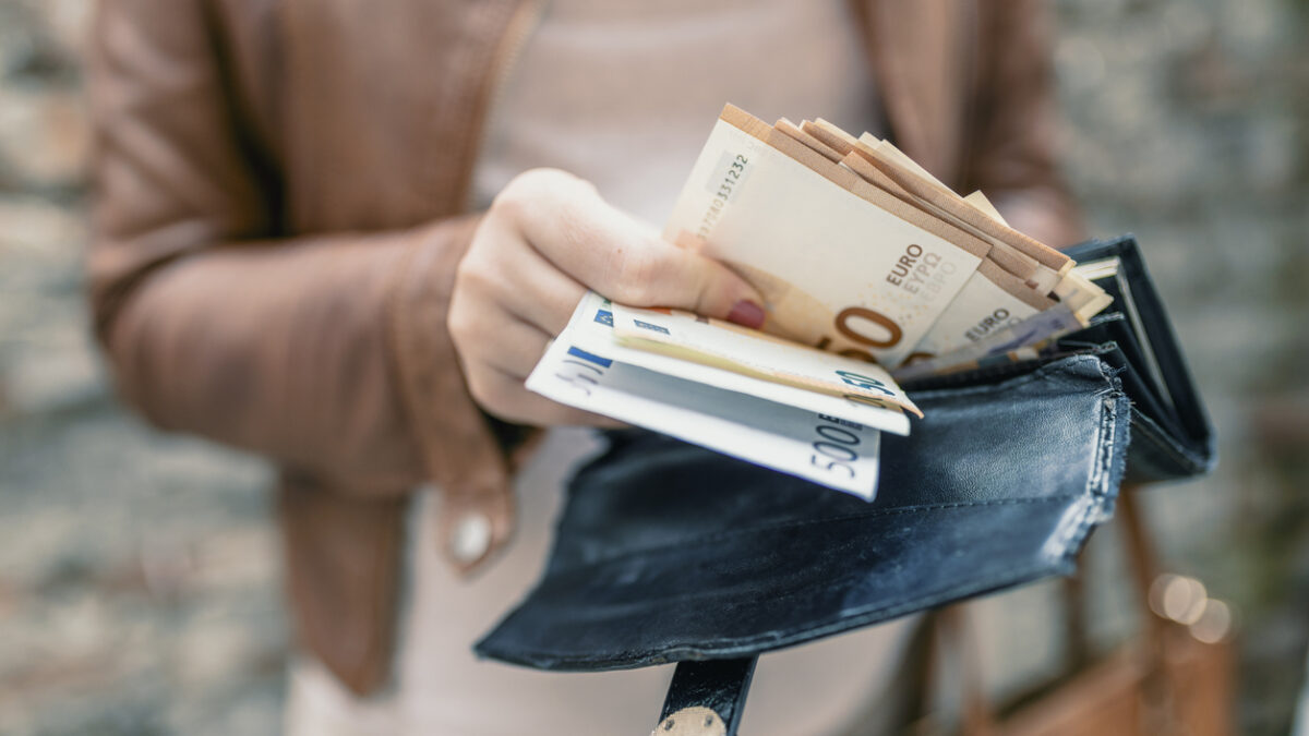 Woman holding in hands wallet with euro money. City girl is taking out money from wallet