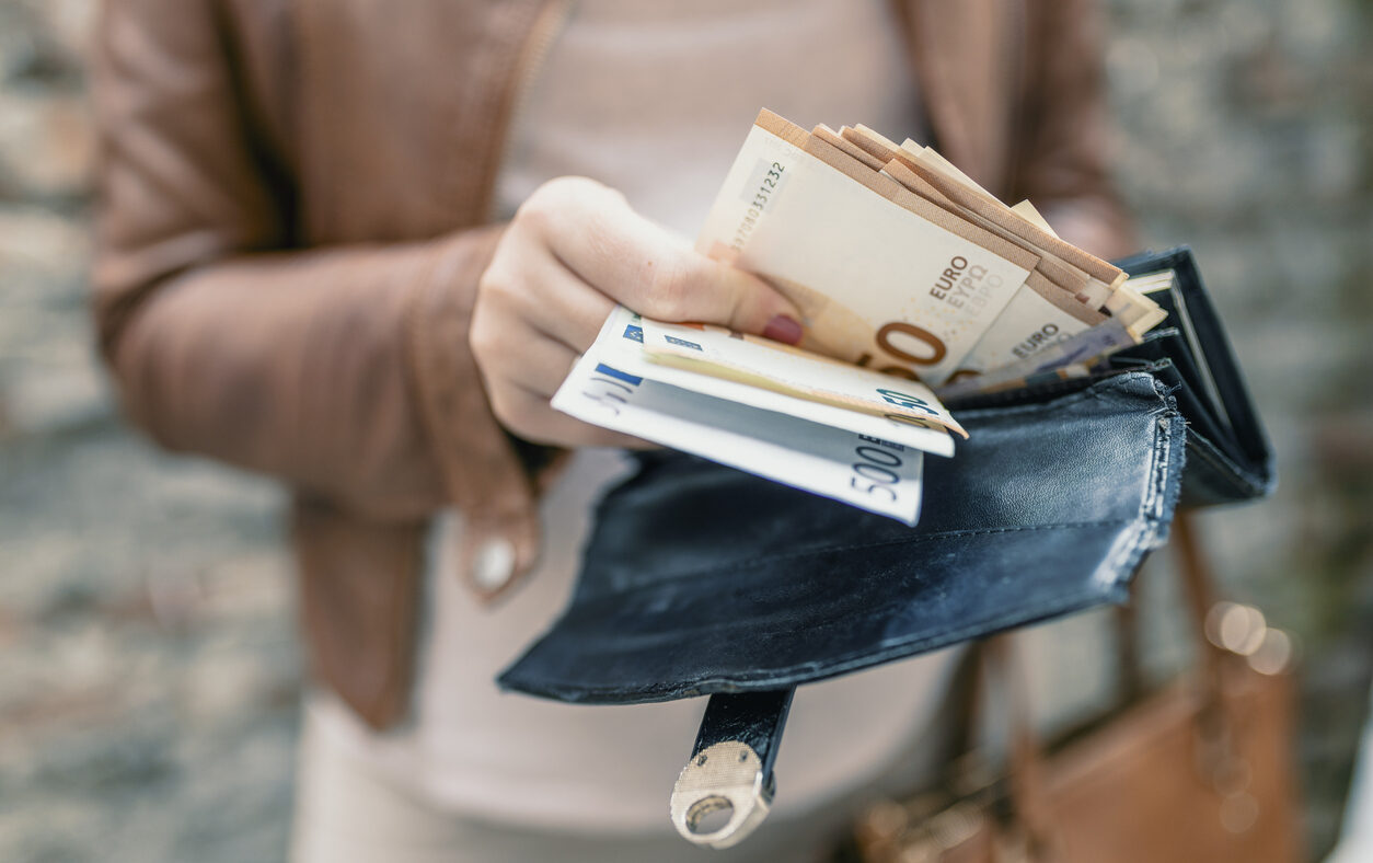 Woman holding in hands wallet with euro money. City girl is taking out money from wallet