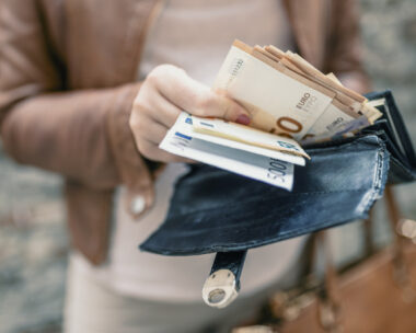 Woman holding in hands wallet with euro money. City girl is taking out money from wallet