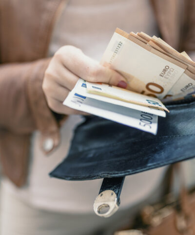Woman holding in hands wallet with euro money. City girl is taking out money from wallet