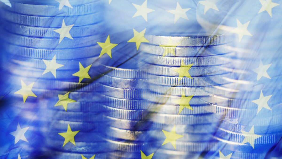 a multiple exposure of some piles of euro coins and a flag of the European Union