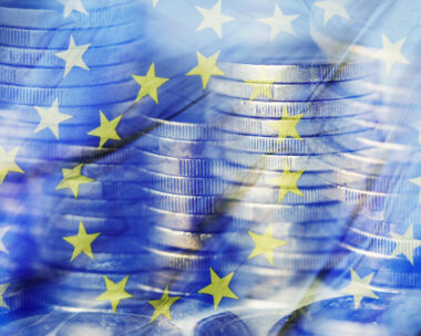 a multiple exposure of some piles of euro coins and a flag of the European Union