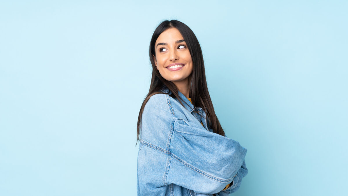 Young caucasian woman isolated on blue background looking to the side and smiling