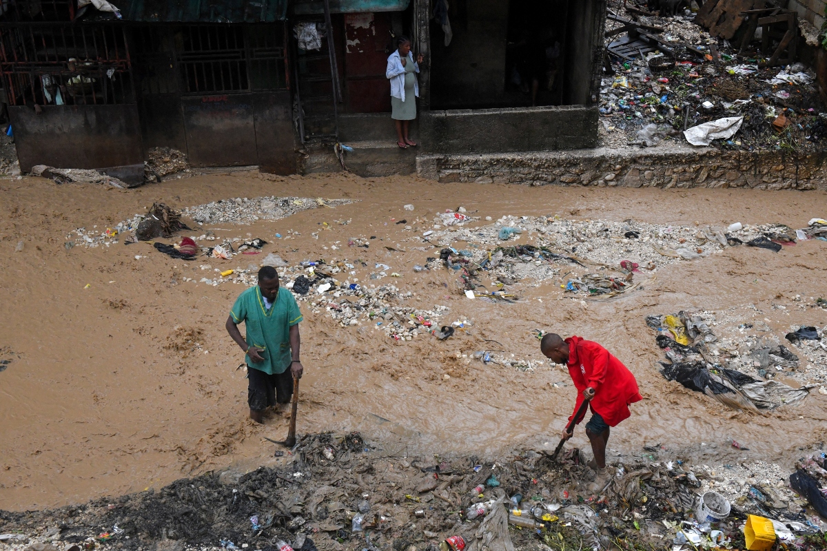 Άνθρωποι καθαρίζουν λασπωμένο δρόμο