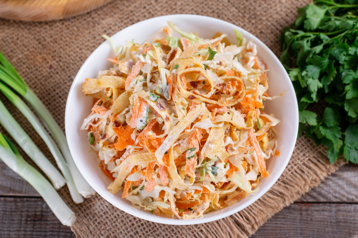 Salad with cabbage and carrots in a white plate on the table