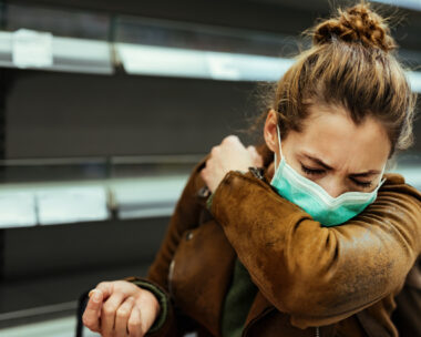 Sick woman buying in supermarket and coughing into elbow during COVID-19 pandemic.