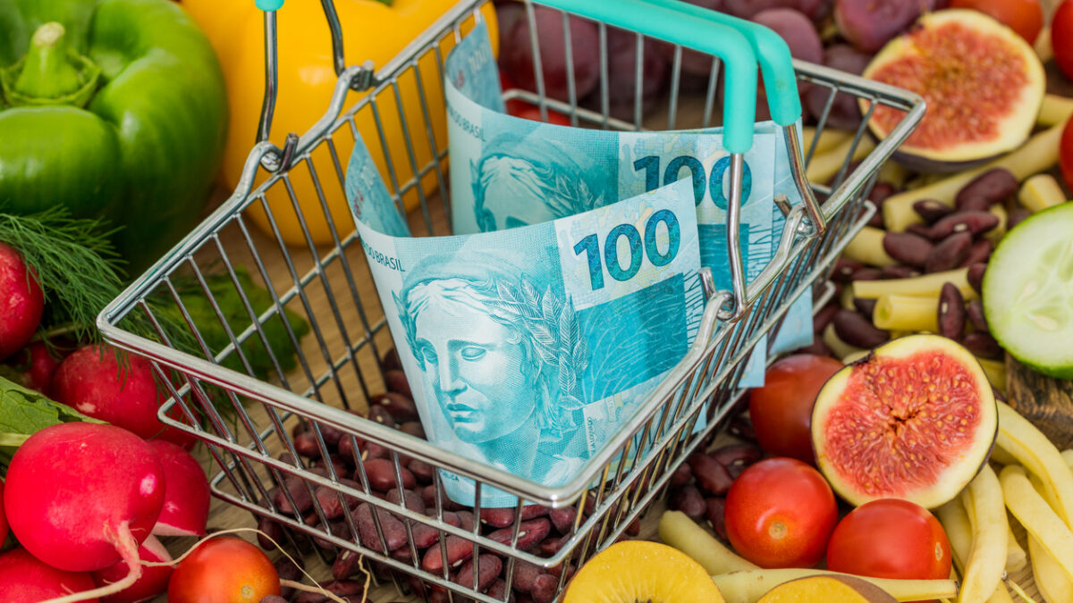 Shopping basket with Brazilian money, around food products, vegetables and fruits. The concept of inflation, rising prices and more expensive food