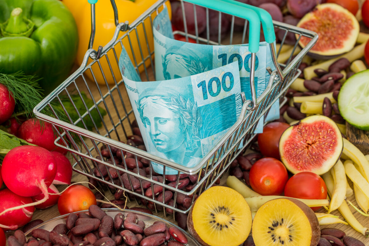 Shopping basket with Brazilian money, around food products, vegetables and fruits. The concept of inflation, rising prices and more expensive food