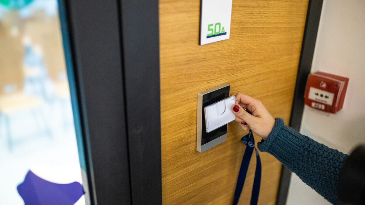 Unrecognizable Caucasian female staff using ID enter key to open the door at the building