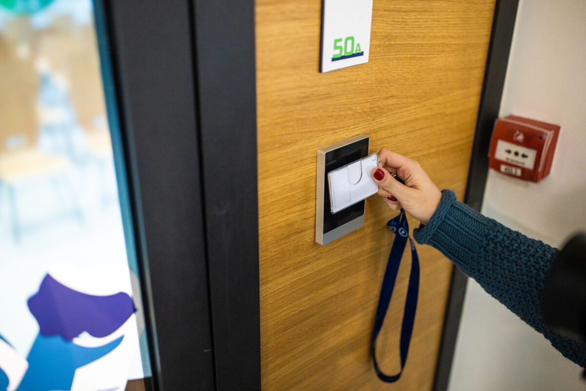 Unrecognizable Caucasian female staff using ID enter key to open the door at the building