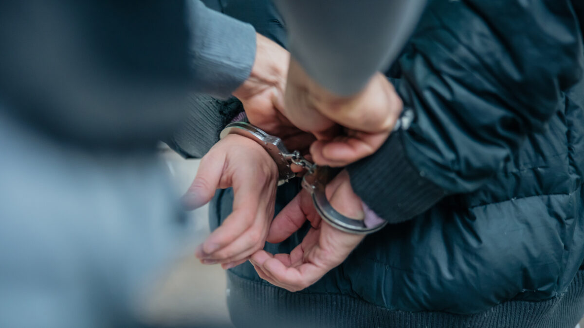 Policeman unlocking a handcuffs on the criminal's back.
