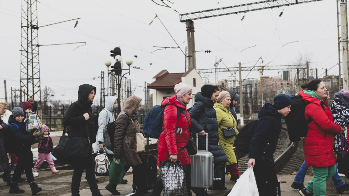 Lviv, Ukraine - March 3, 2022: Having just disembarked a train, people walk with their luggage across the tracks in Lviv.