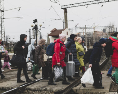 Lviv, Ukraine - March 3, 2022: Having just disembarked a train, people walk with their luggage across the tracks in Lviv.