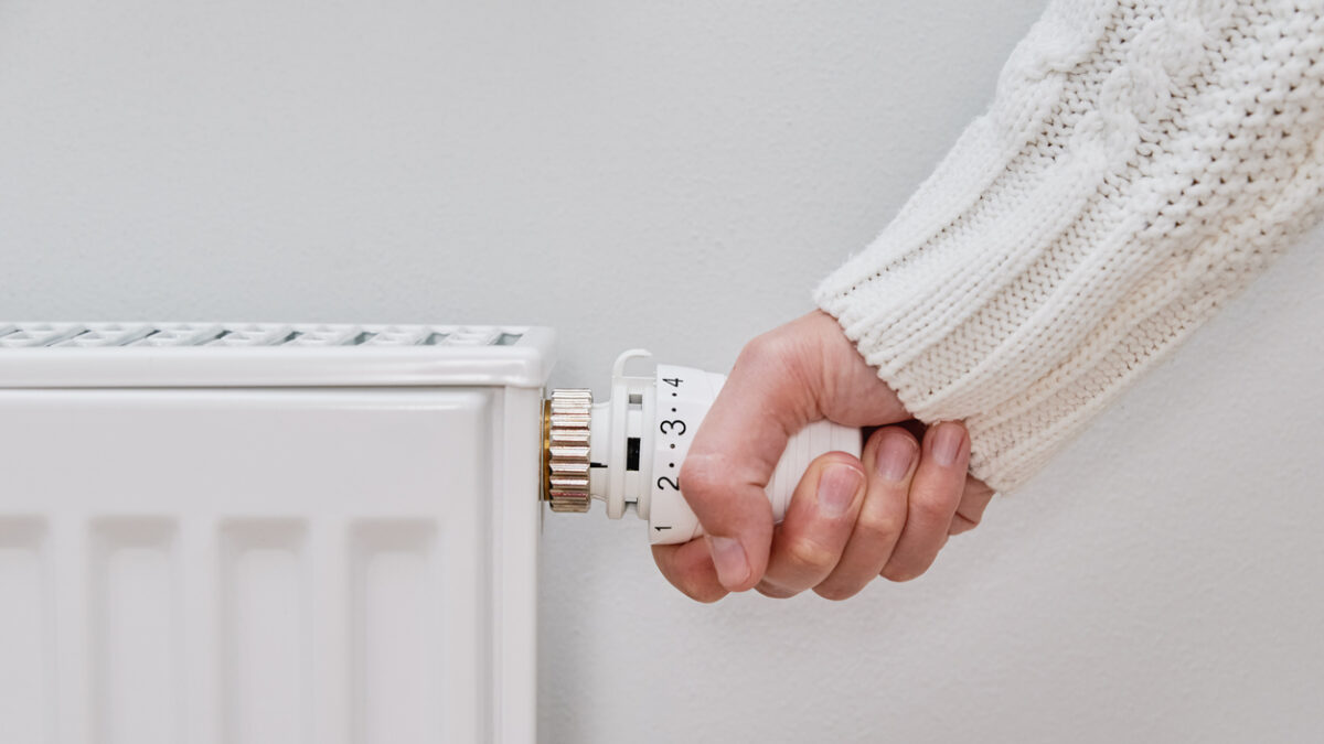 Woman adjusting temperature on heating radiator, Energy crisis concept in Europe, Rising costs in private households for gas bill due to inflation and war
