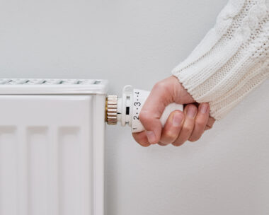 Woman adjusting temperature on heating radiator, Energy crisis concept in Europe, Rising costs in private households for gas bill due to inflation and war