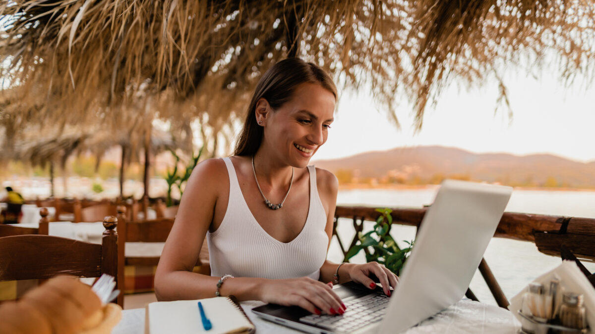 Young woman studying and using a laptop in a restaurant during a vacation at the seaside