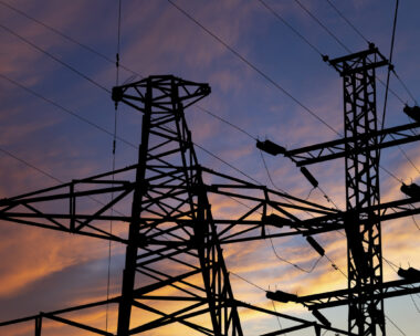 Electricity pylon (high voltage power line), black contour, against the background of a romantic evening sky