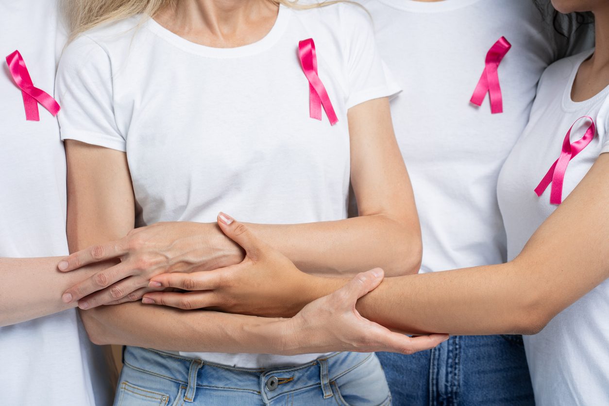 Women in pink ribbons unite, holding hands for breast cancer awareness, closeup. Showing strength, hope, and support in a powerful image of community