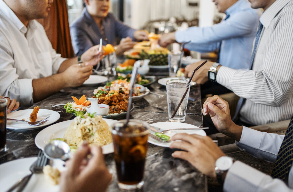 Cropped shot of group of business professionals gathered at a restaurant having dinner together after work