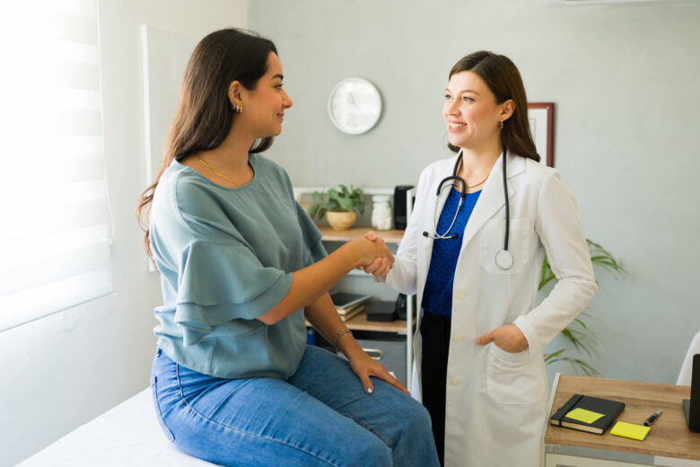 Female doctor happily shaking hands with her hispanic patient after a successful consultation in her office