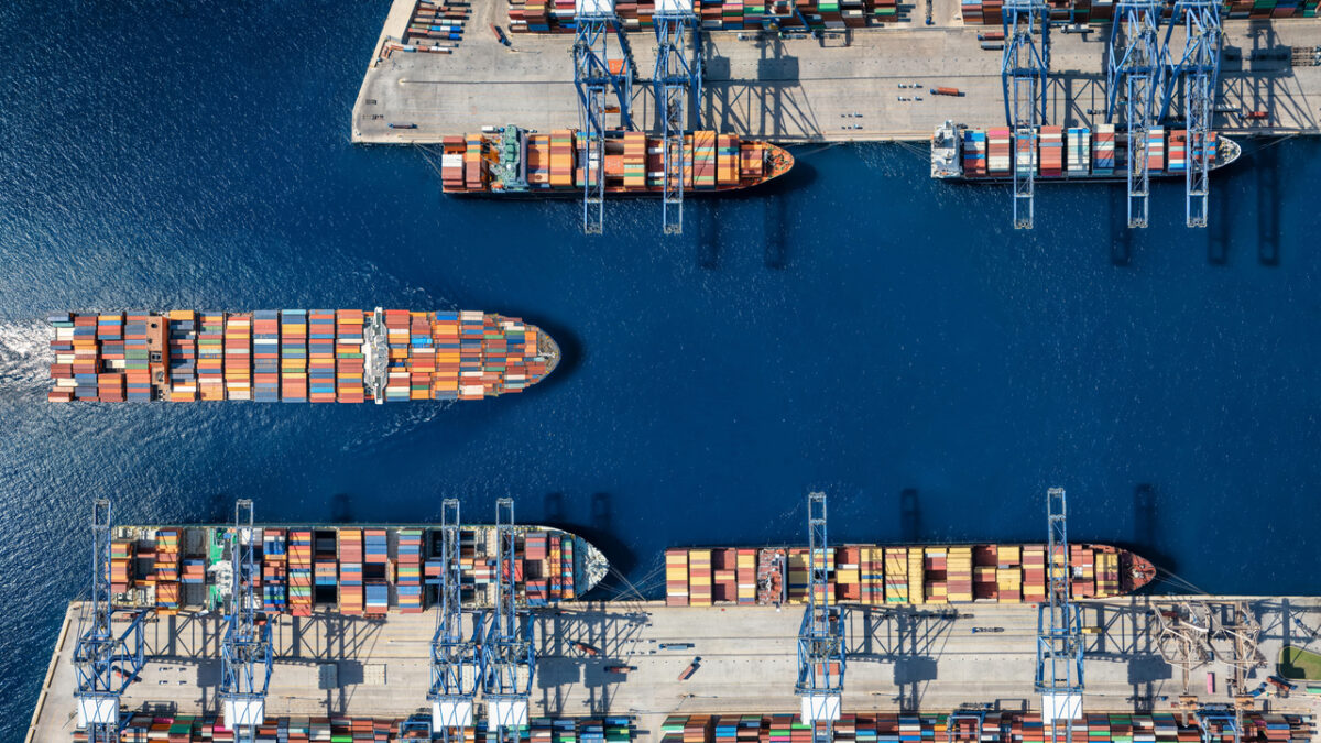 Aerial top down view of a large container cargo ship terminal harbor with loading activity and vessel traffic
