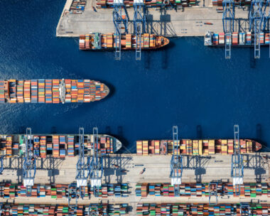 Aerial top down view of a large container cargo ship terminal harbor with loading activity and vessel traffic