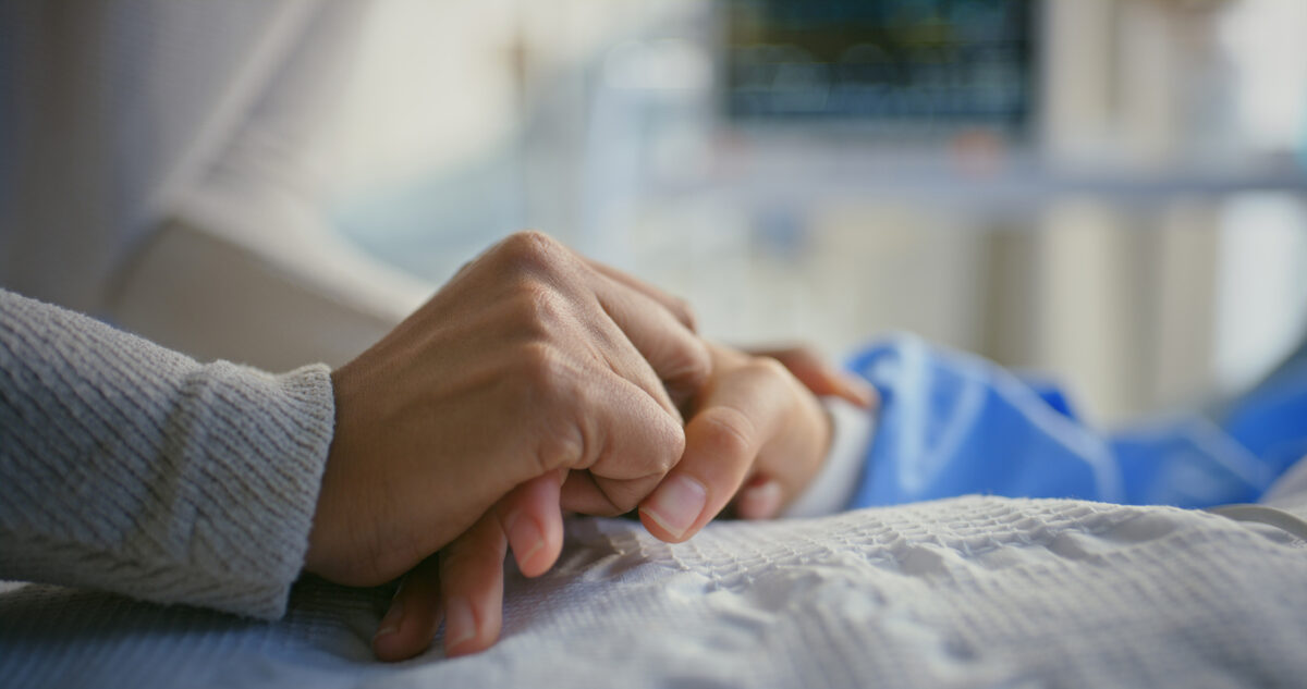 Holding hands, patient and person by hospital bed for support, sick and empathy for wellness. People, care and console for health with connection, love and help with comfort for recovery at clinic