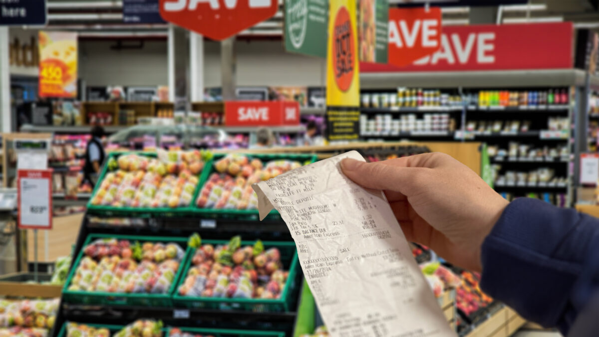 Close-up on a woman shopping at a grocery store and checking her receipt while exiting