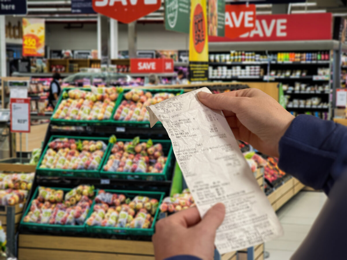 Close-up on a woman shopping at a grocery store and checking her receipt while exiting