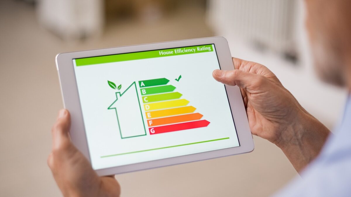 Hand holding digital tablet and looking at house efficiency rating. Detail of house efficiency rating on digital tablet screen. Concept of ecological and bio energetic house. Energy class.