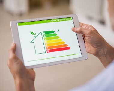 Hand holding digital tablet and looking at house efficiency rating. Detail of house efficiency rating on digital tablet screen. Concept of ecological and bio energetic house. Energy class.