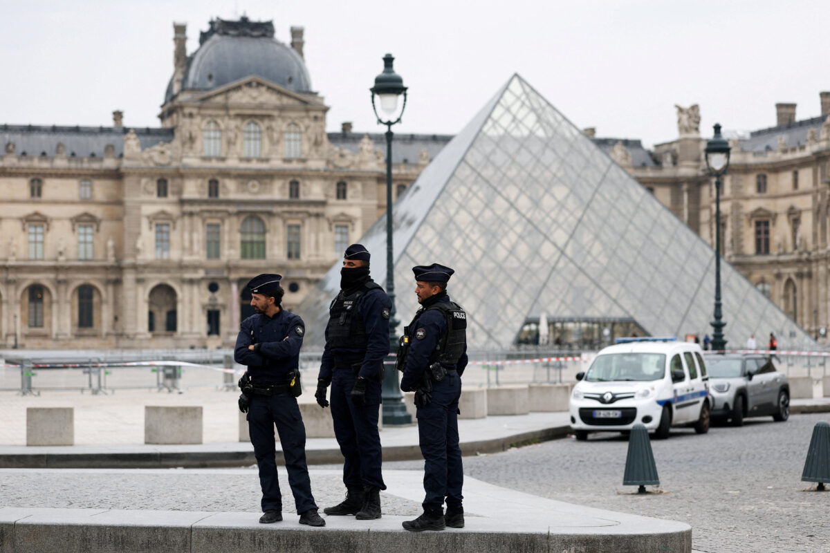 Police officers stand near the pyramid of the Louvre museum after reports of a robbery, in Paris, France, October 19, 2025. REUTERS