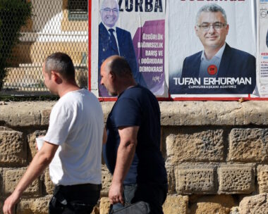 Τουρκοκύπριοι περνούν μπροστά από προεκλογική αφίσα του Tufan Erhurman
