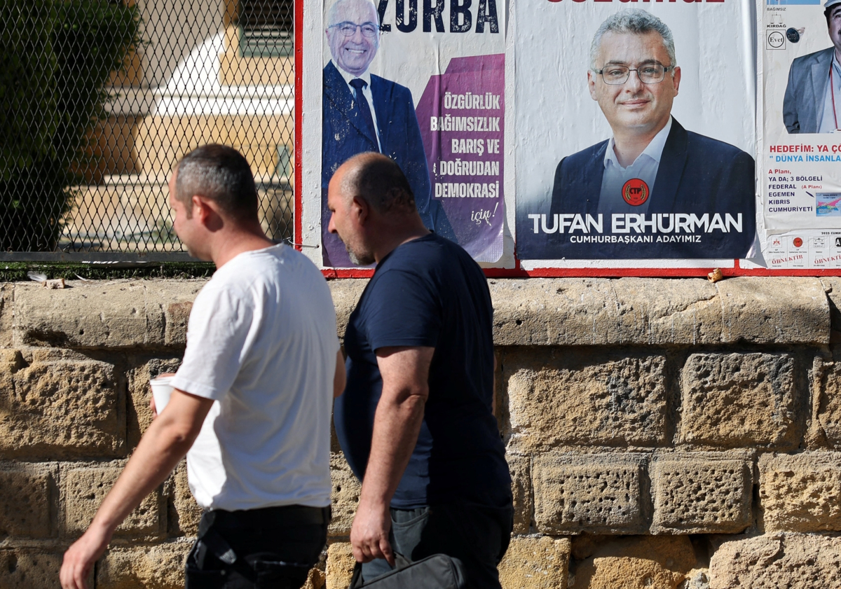Τουρκοκύπριοι περνούν μπροστά από προεκλογική αφίσα του Tufan Erhurman