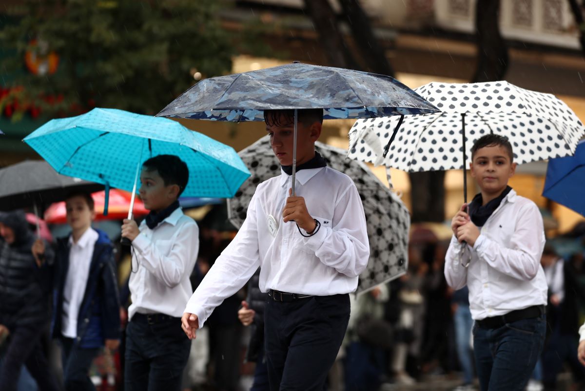 Elementary school students march holding umbrellas